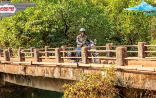 Motorradfahrer fährt über eine Brücke in Indien