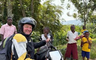 Motorradfahrer und einheimische Kinder in Afrika