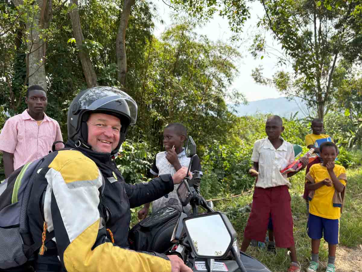 Motorradfahrer und einheimische Kinder in Afrika
